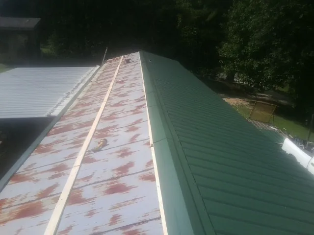 Old rusted panels beside newly installed green metal roofing — Wind Damage Roof Repair by Roofing Brothers in Bethel Springs