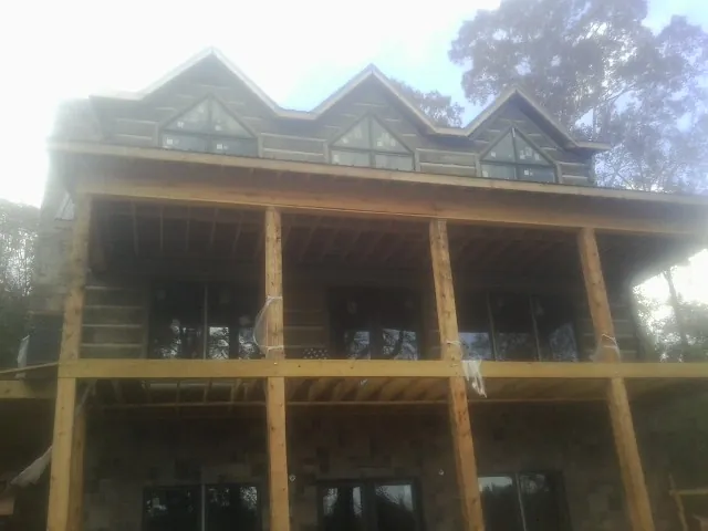Dormers and porch framing on a large log home under construction — Roof Coating work by our crew in Bethel Springs
