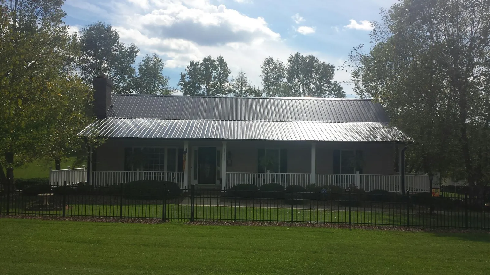 Gray metal roof on a brick ranch with a full width front porch — Gutter Guard Installation work by our crew in Bethel Springs