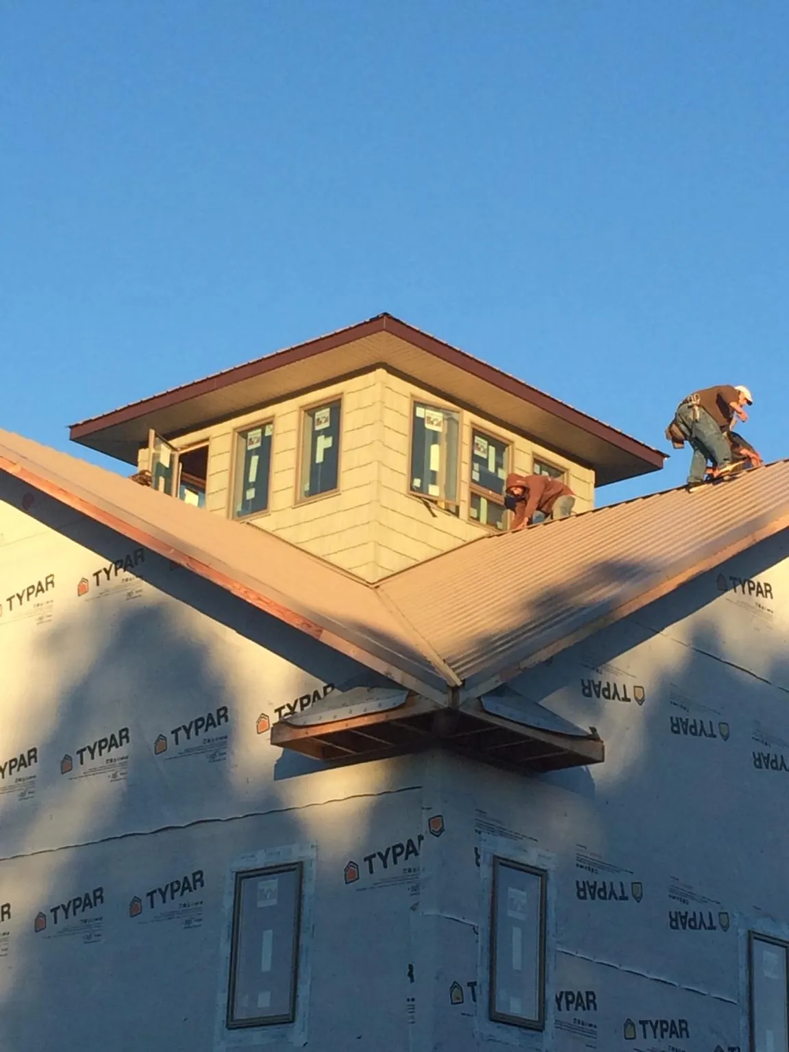 Roofers working around a rooftop cupola on a new metal roof at sunset — Roof Waterproofing in Bethel Springs by Roofing Brothers